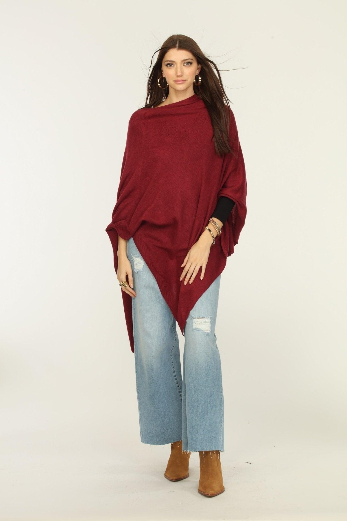 woman wearing burgundy poncho, jeans, and tan boots