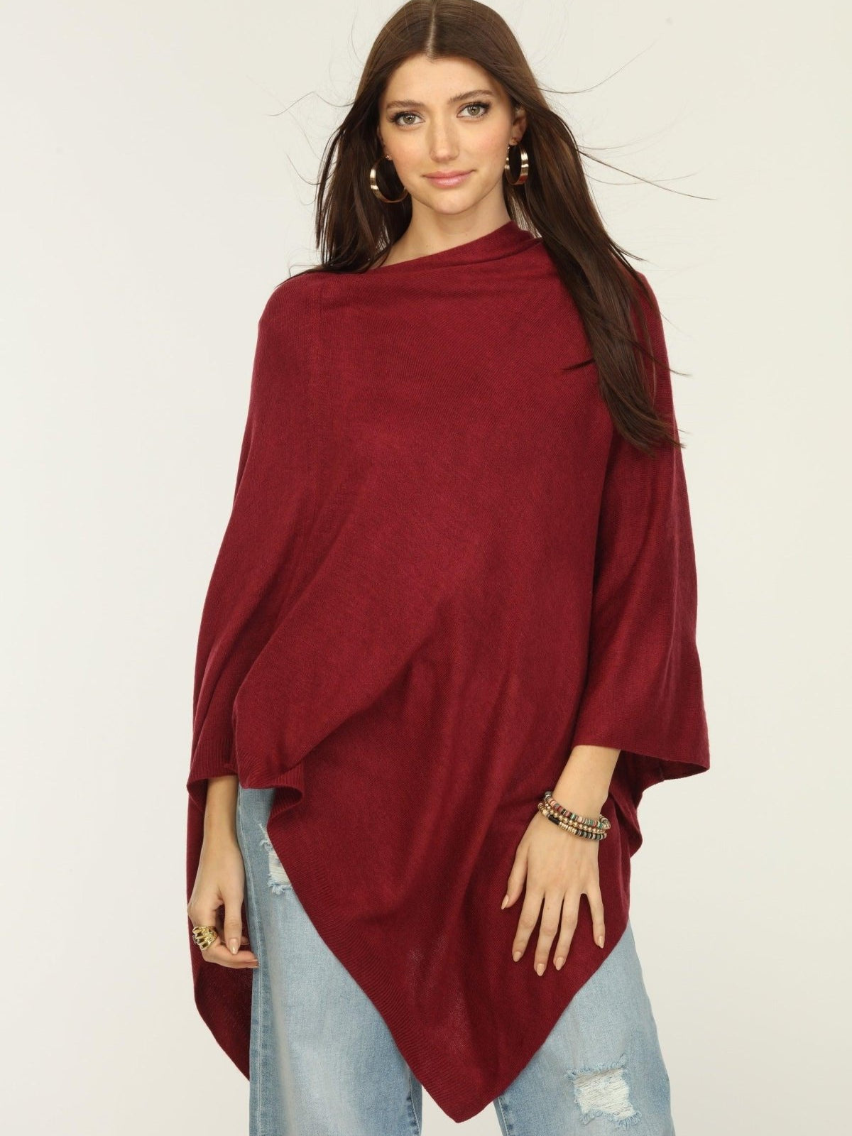 woman wearing burgundy poncho and jeans