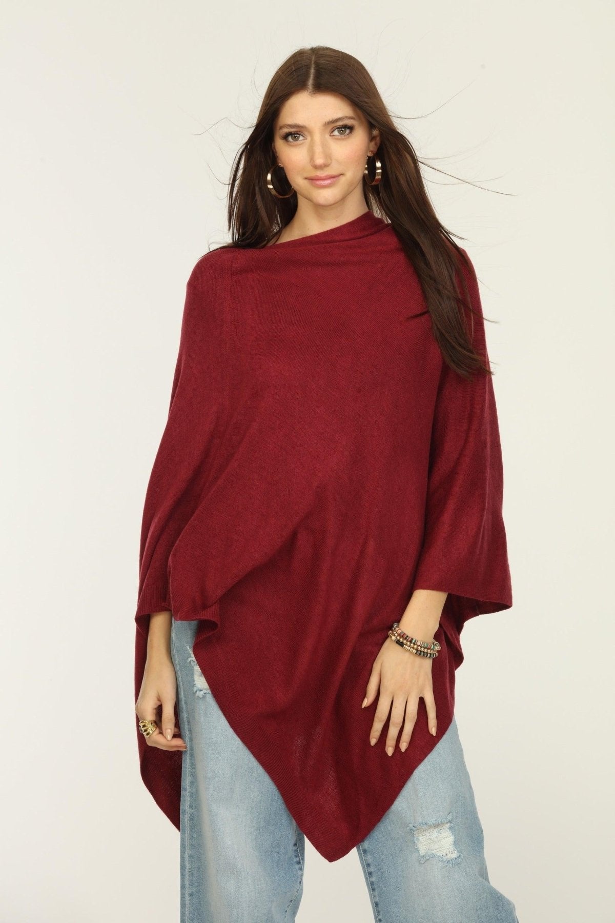 woman wearing burgundy poncho and jeans