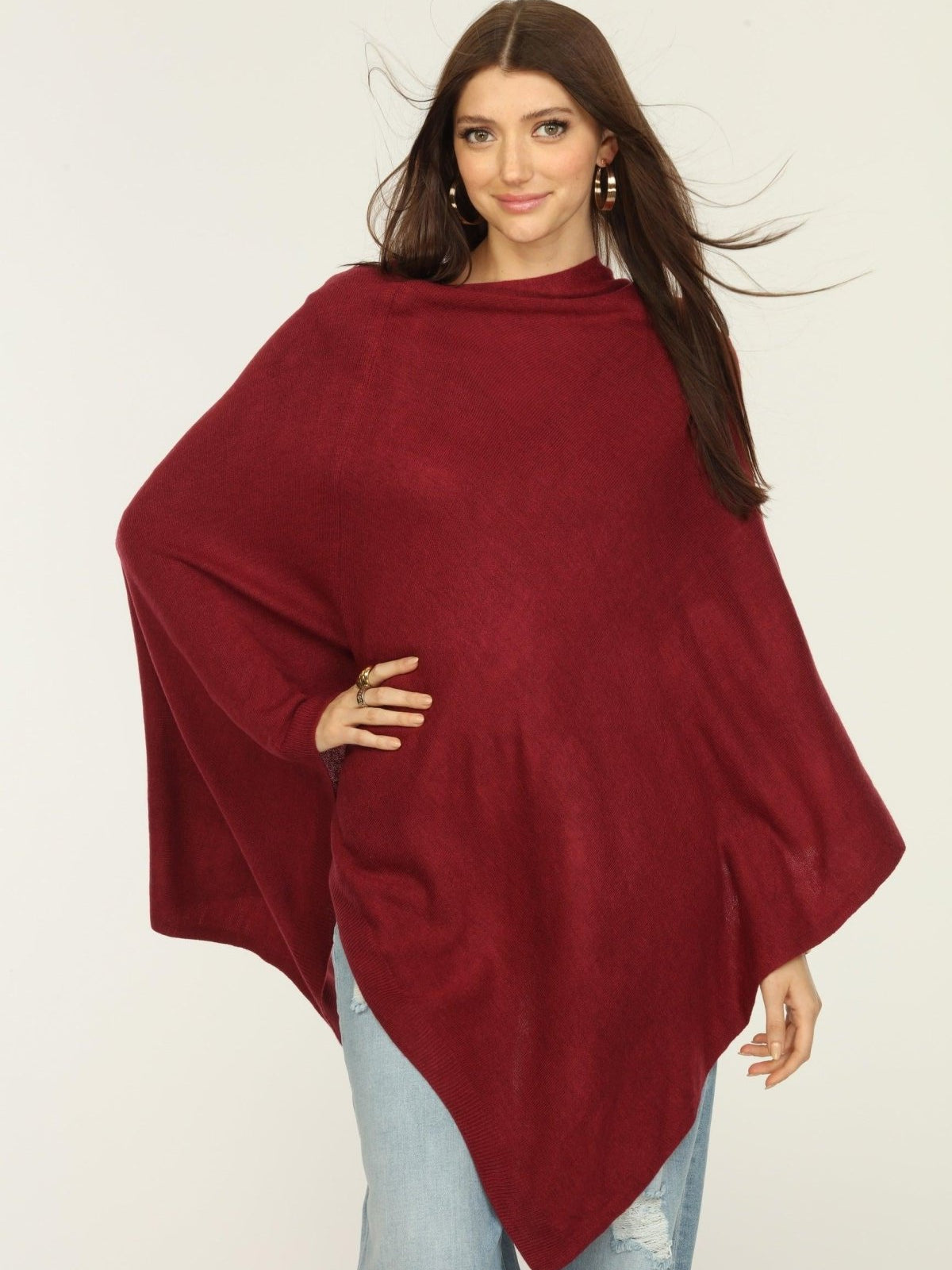 woman wearing burgundy poncho and jeans