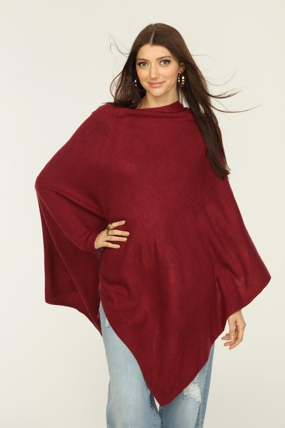 woman wearing burgundy poncho and jeans