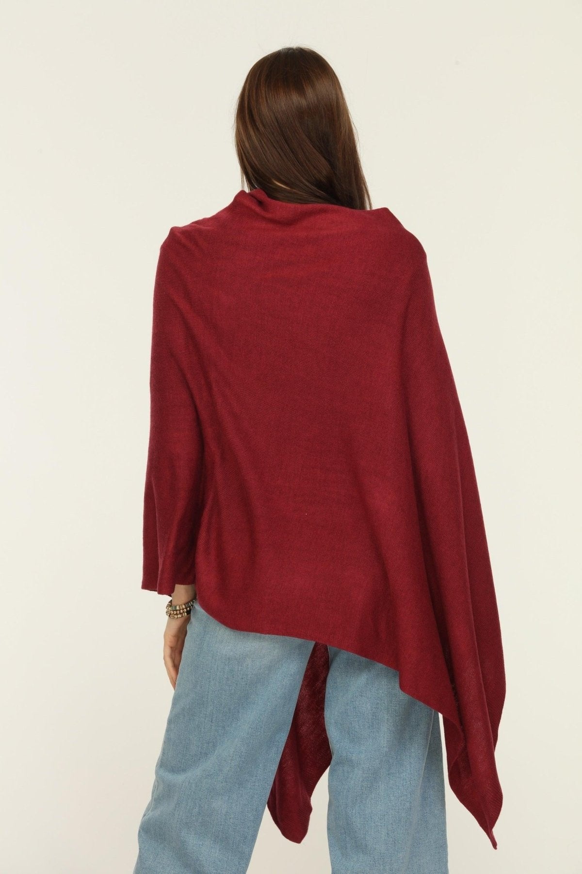 back side of woman wearing burgundy poncho and jeans