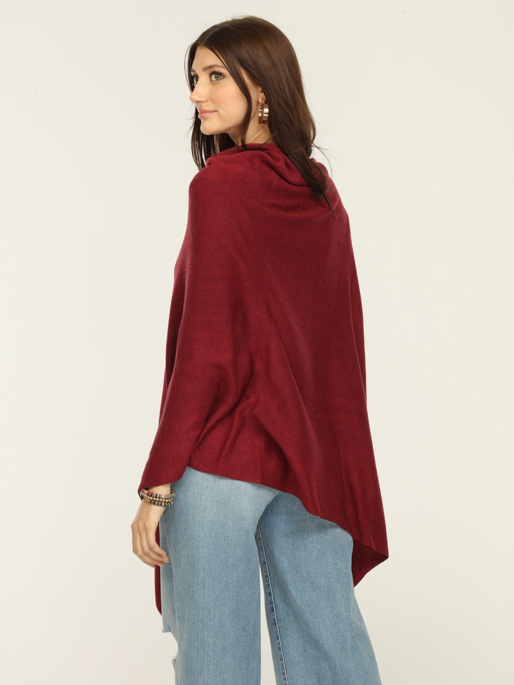 back side of woman wearing burgundy poncho, jeans, and tan boots