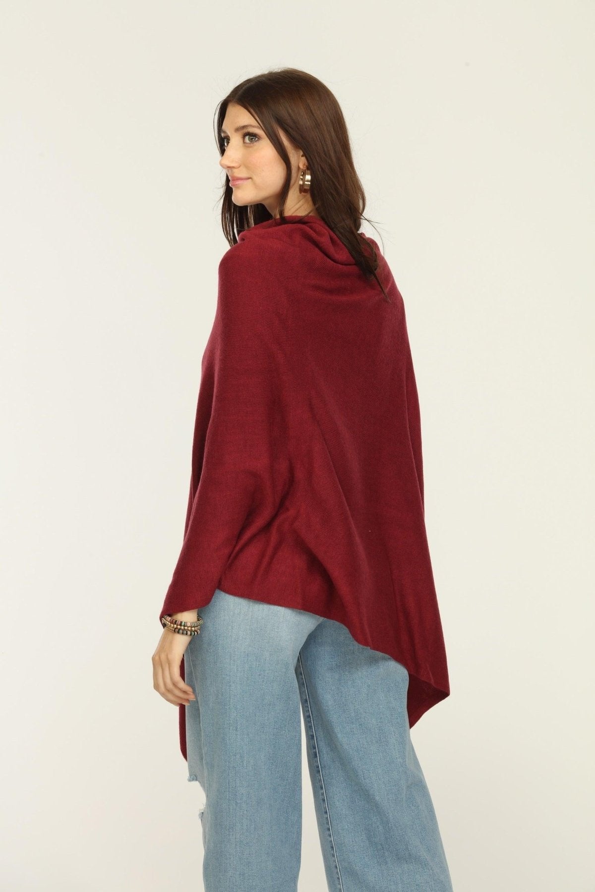 back side of woman wearing burgundy poncho, jeans, and tan boots
