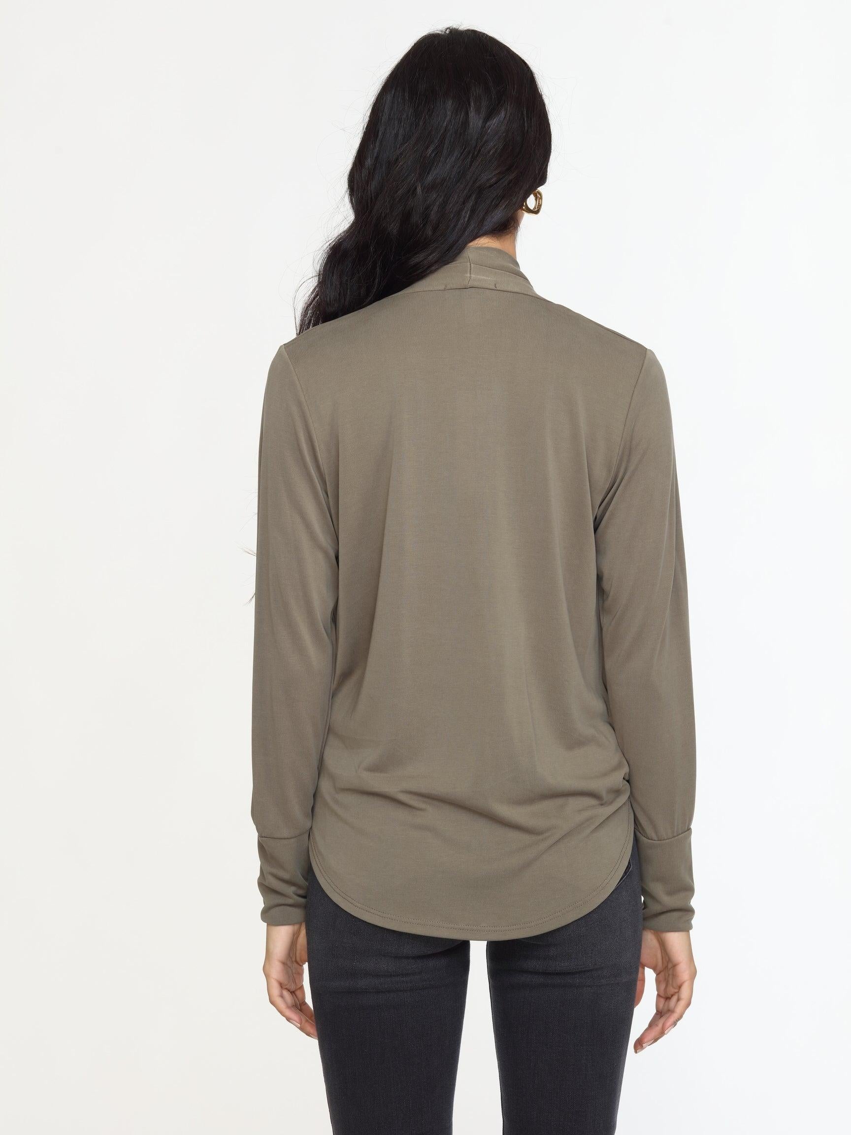 back side of olive long sleeve draped blouse on woman in dark denim pants