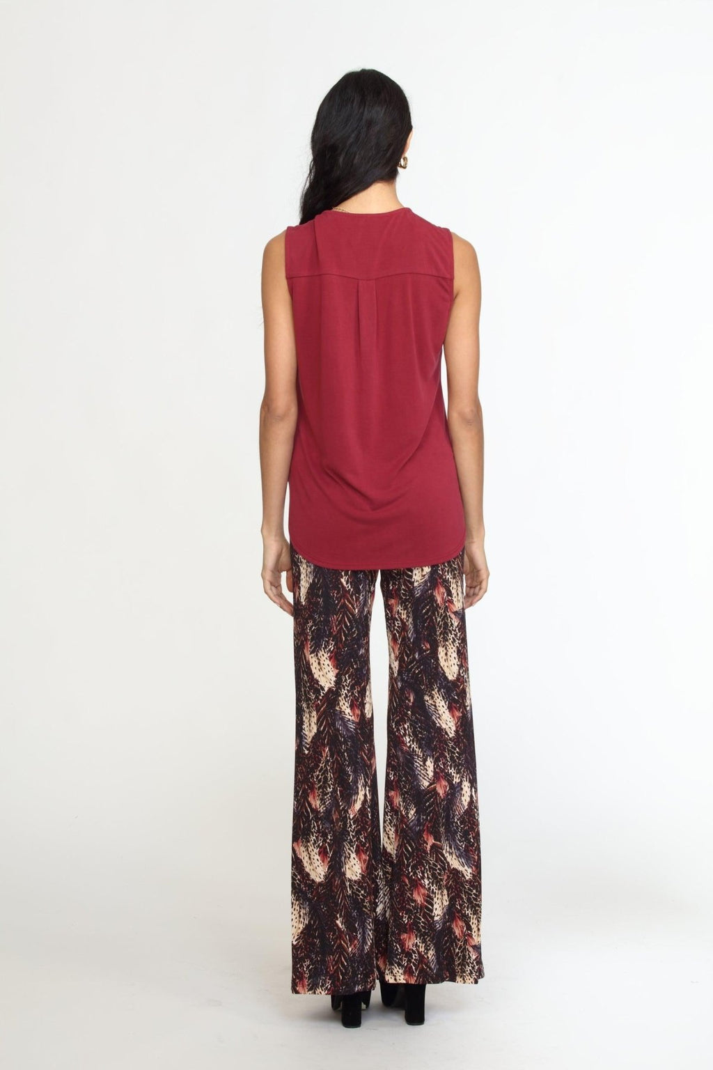 back side of sleeveless burgundy top on woman in multicolored pants