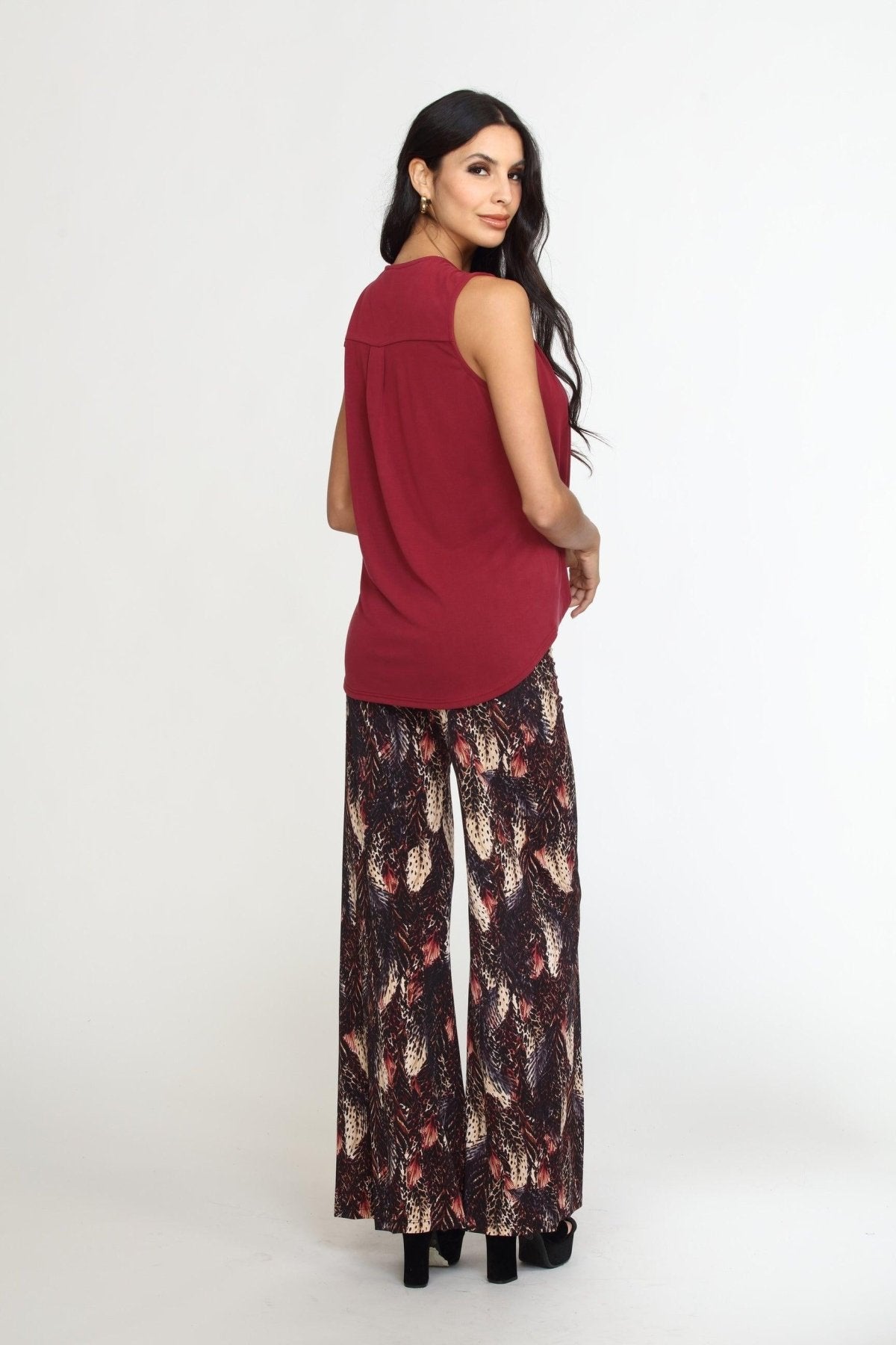 back view of sleeveless burgundy top on woman in multicolored pants