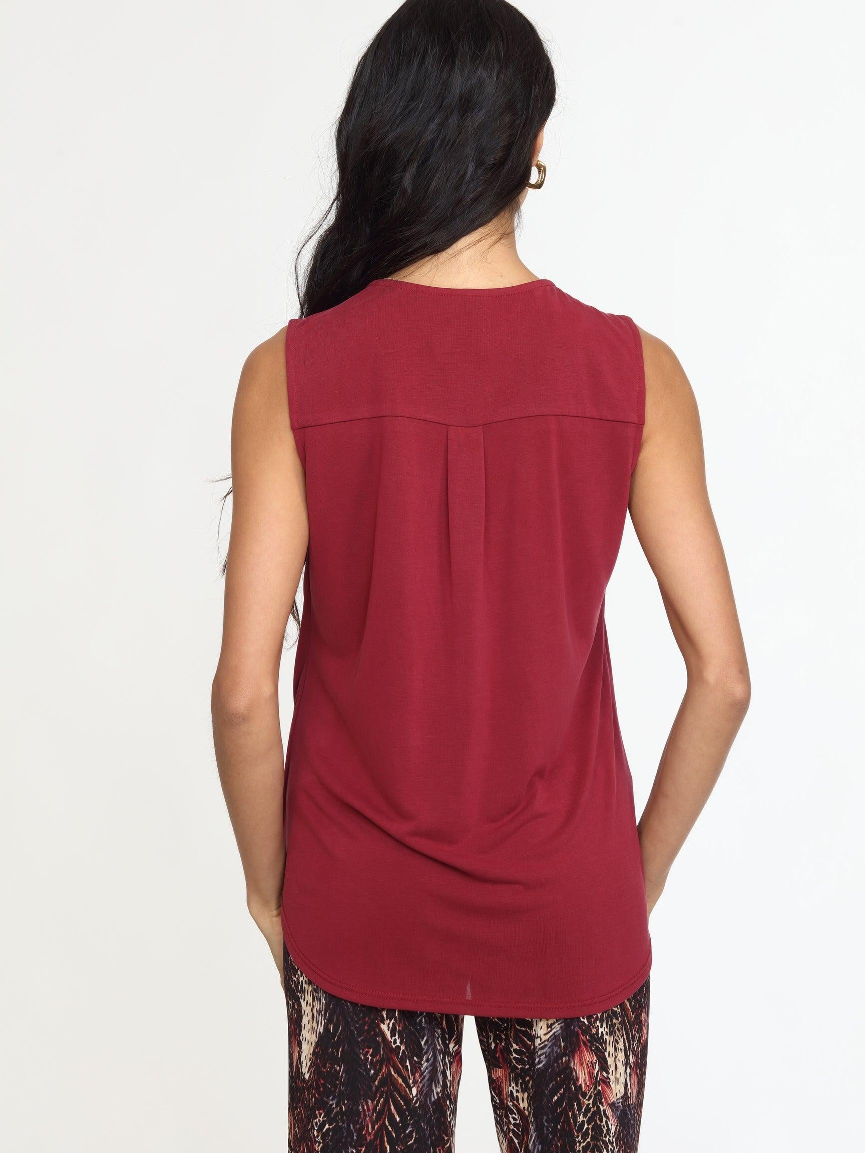 back side of sleeveless burgundy top on woman in multicolored pants