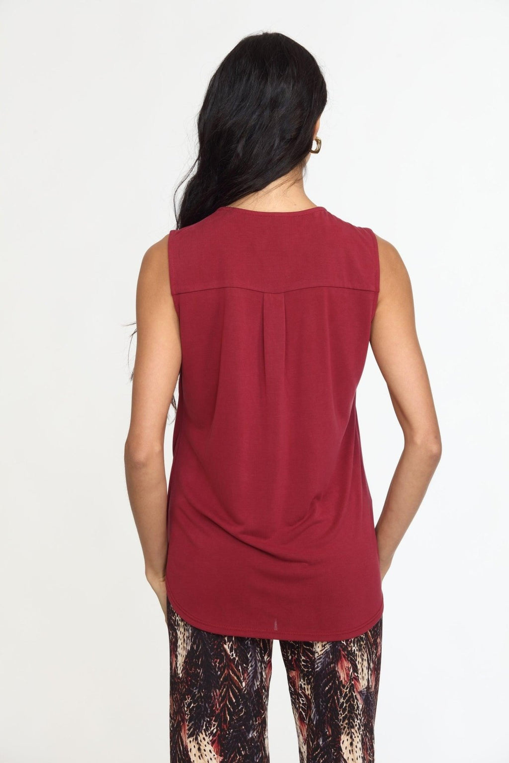 back side of sleeveless burgundy top on woman in multicolored pants