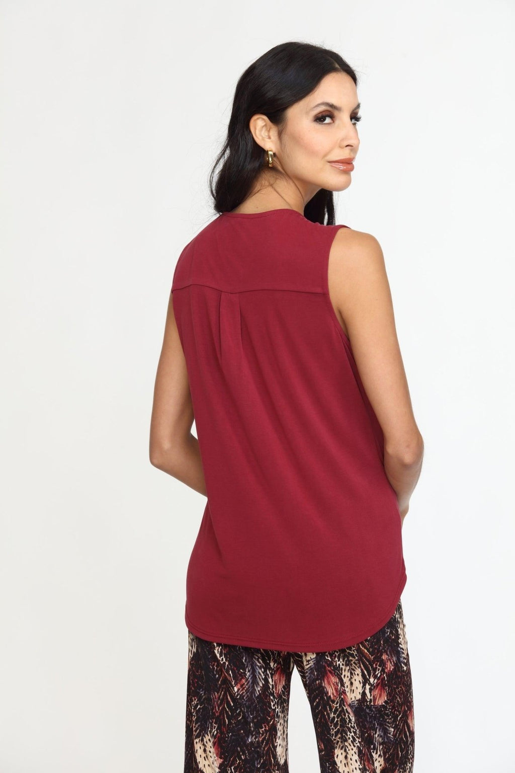 back side of sleeveless burgundy top on woman in multicolored pants