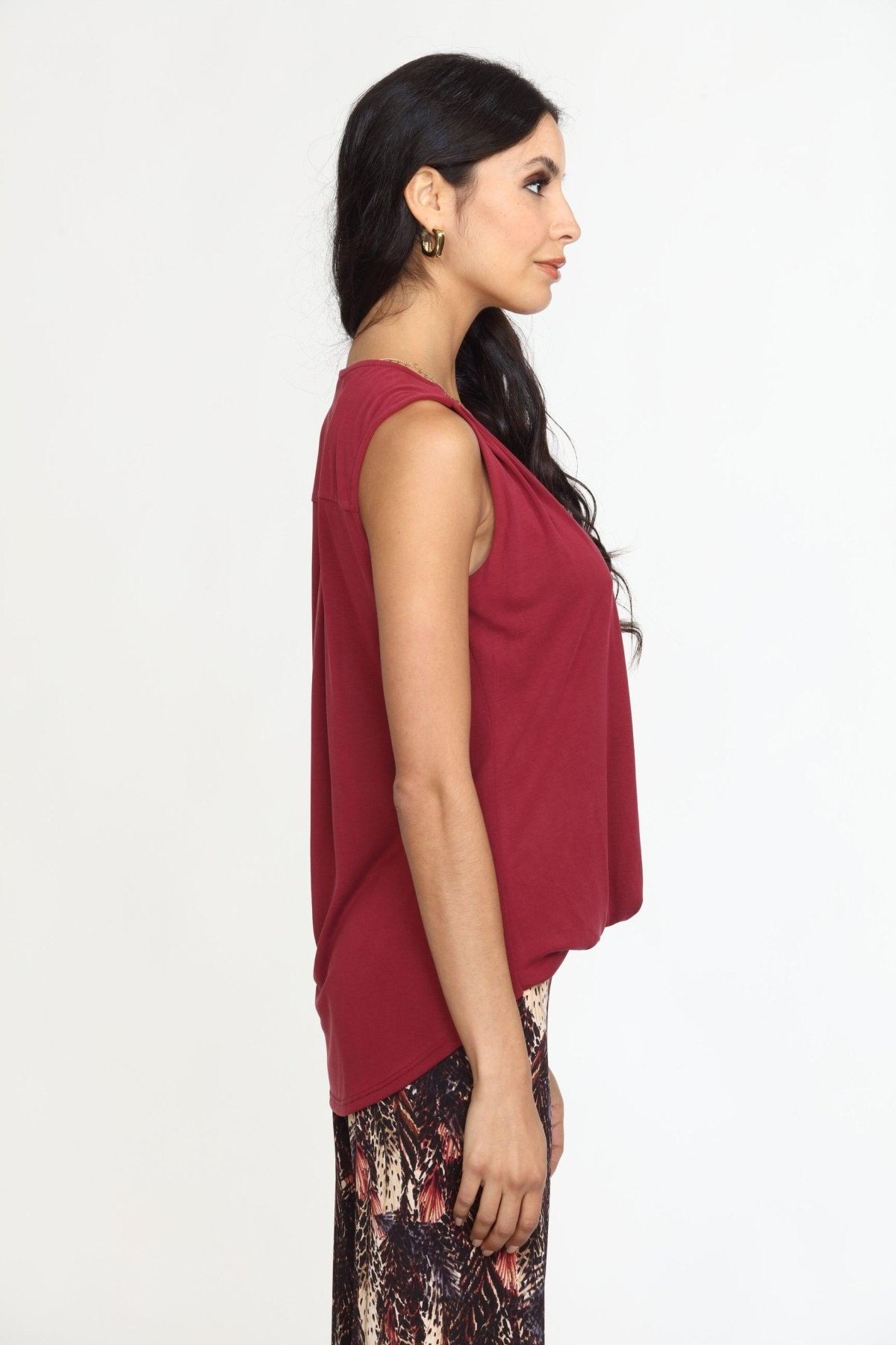 side view of sleeveless burgundy top on woman in multicolored pants