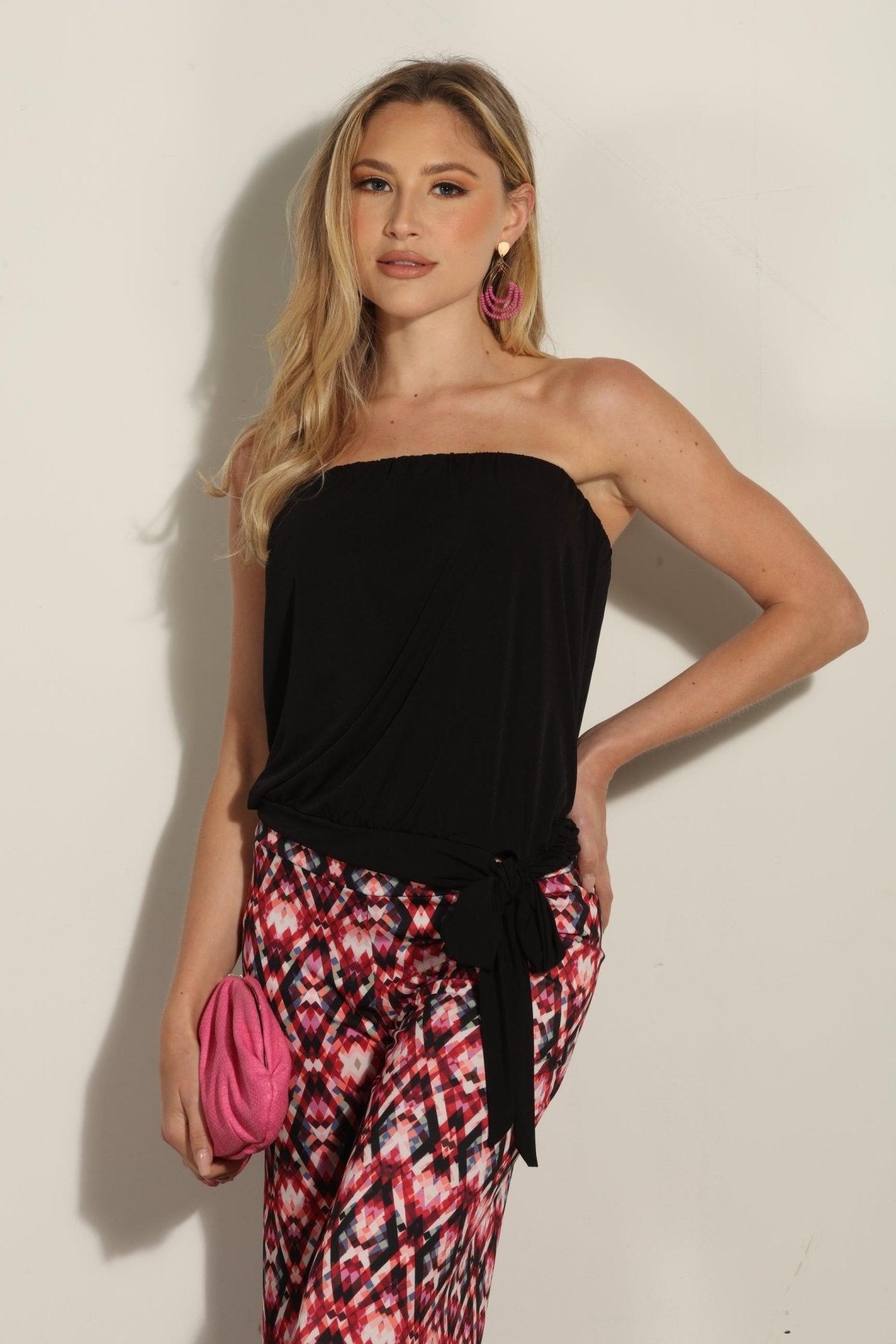 strapless top and multicolored pants on woman holding pink clutch