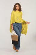 lime green poncho and dark denim jeans on woman holding woven tote bag