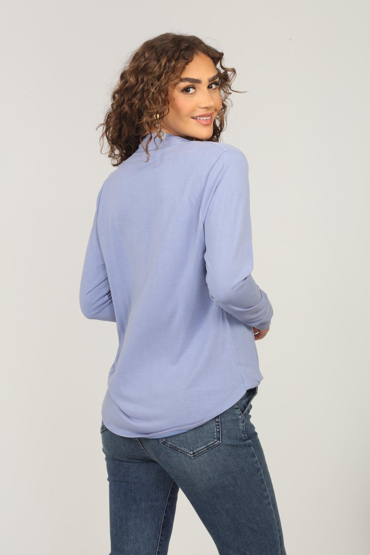 back side of light blue long sleeve draped top styled on woman in denim pants