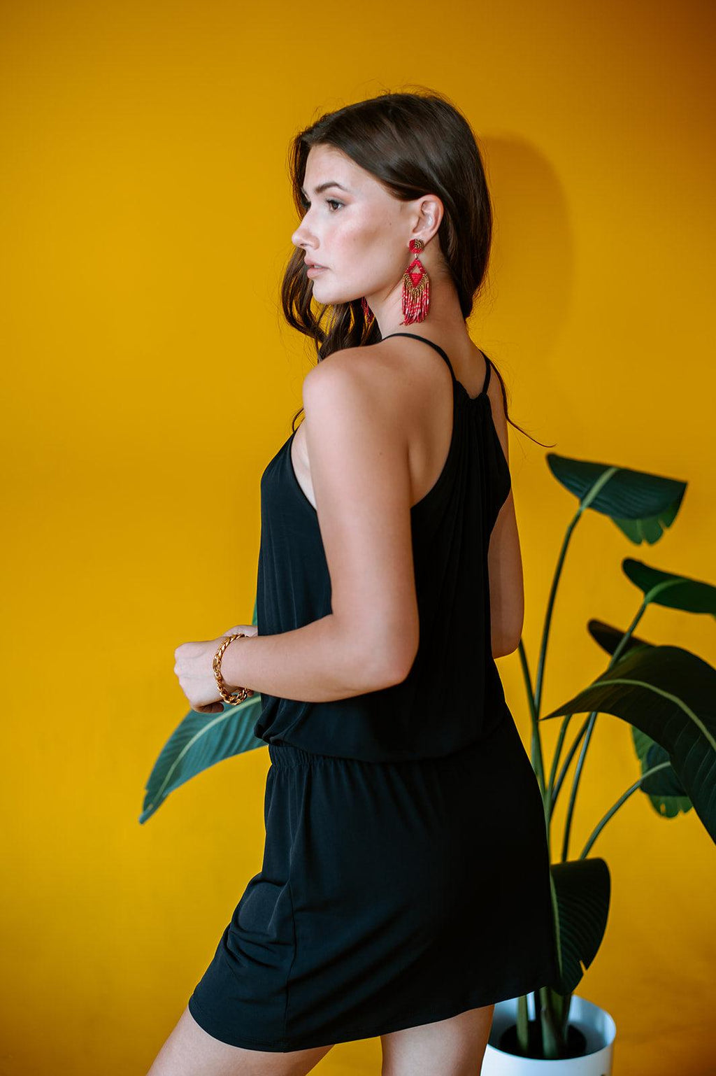 back side of black sleeveless halter dress on woman with yellow background