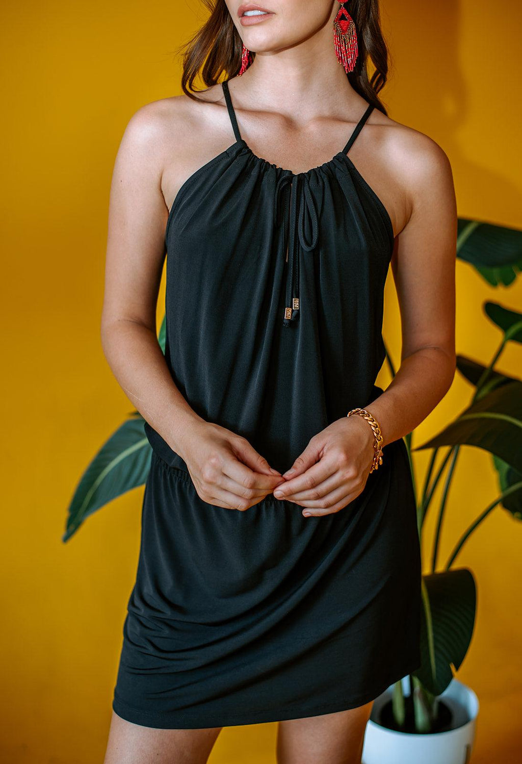 black sleeveless halter dress on woman with yellow background