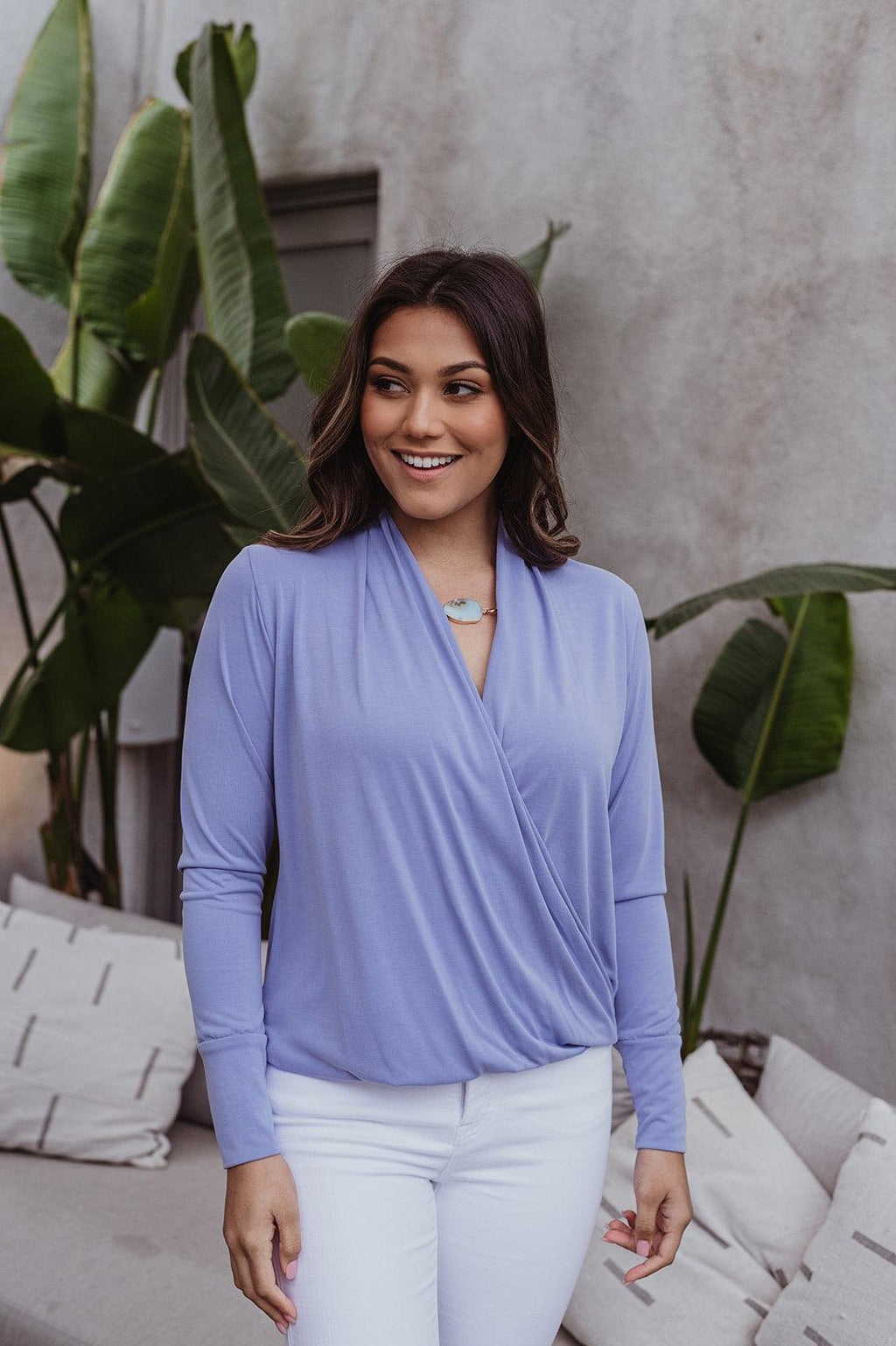 light blue long sleeve draped top styled on woman in white pants