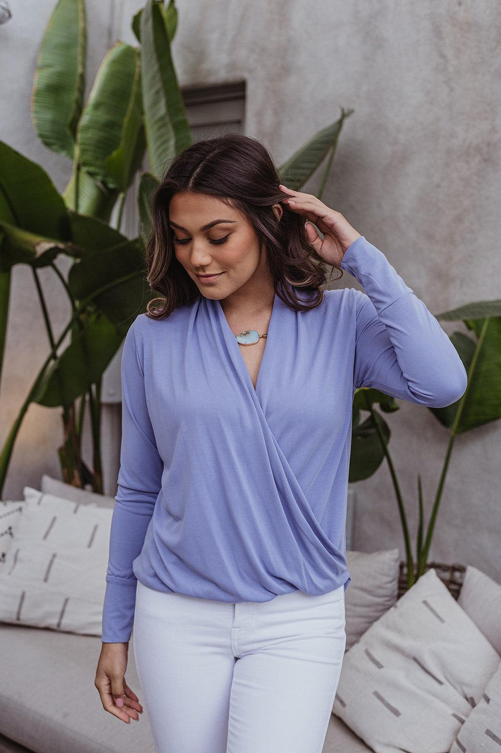 light blue long sleeve draped top styled on woman in white pants
