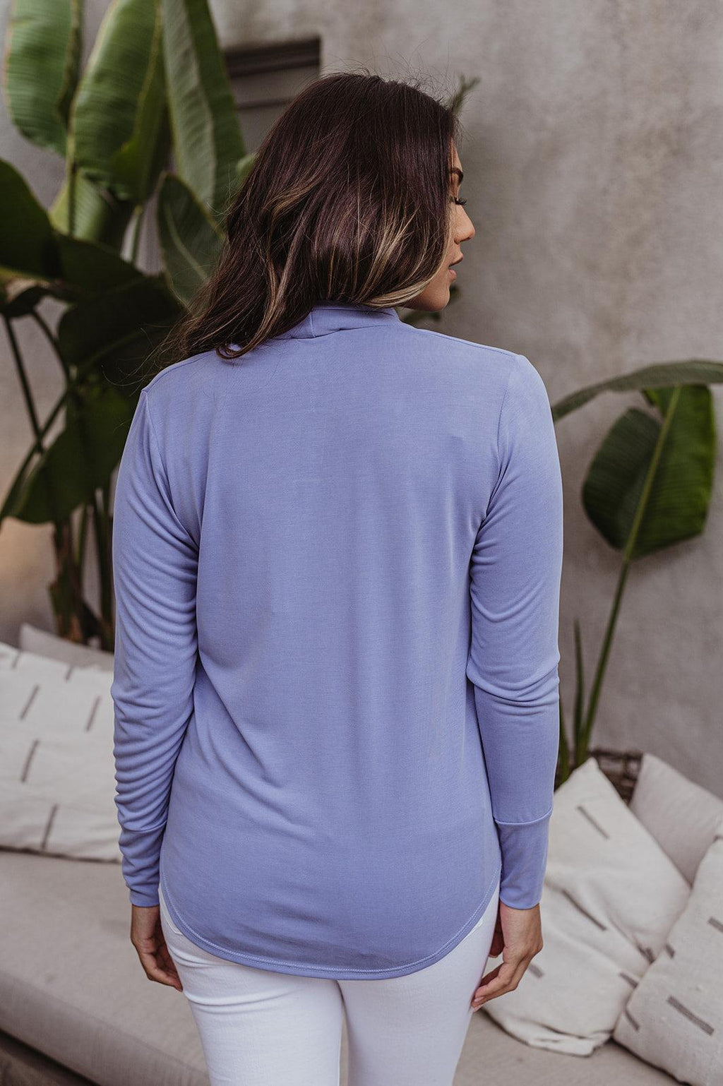 back side of light blue long sleeve draped top styled on woman in white pants