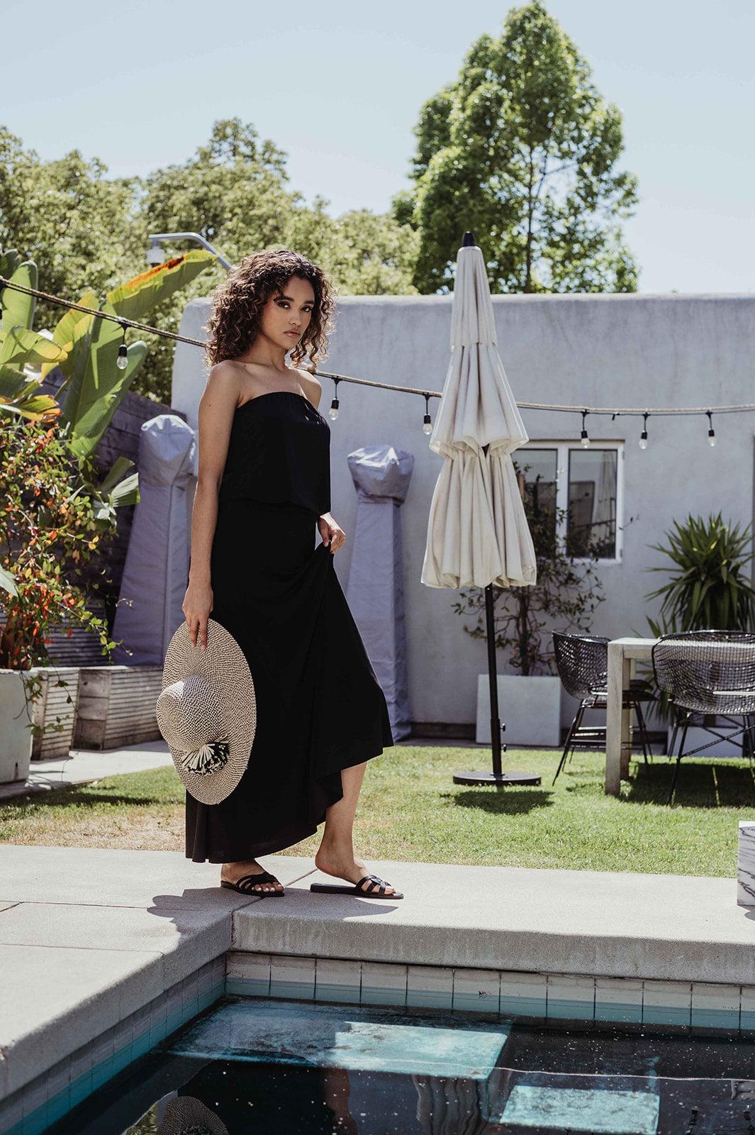 black strapless maxi dress on woman holding large hat