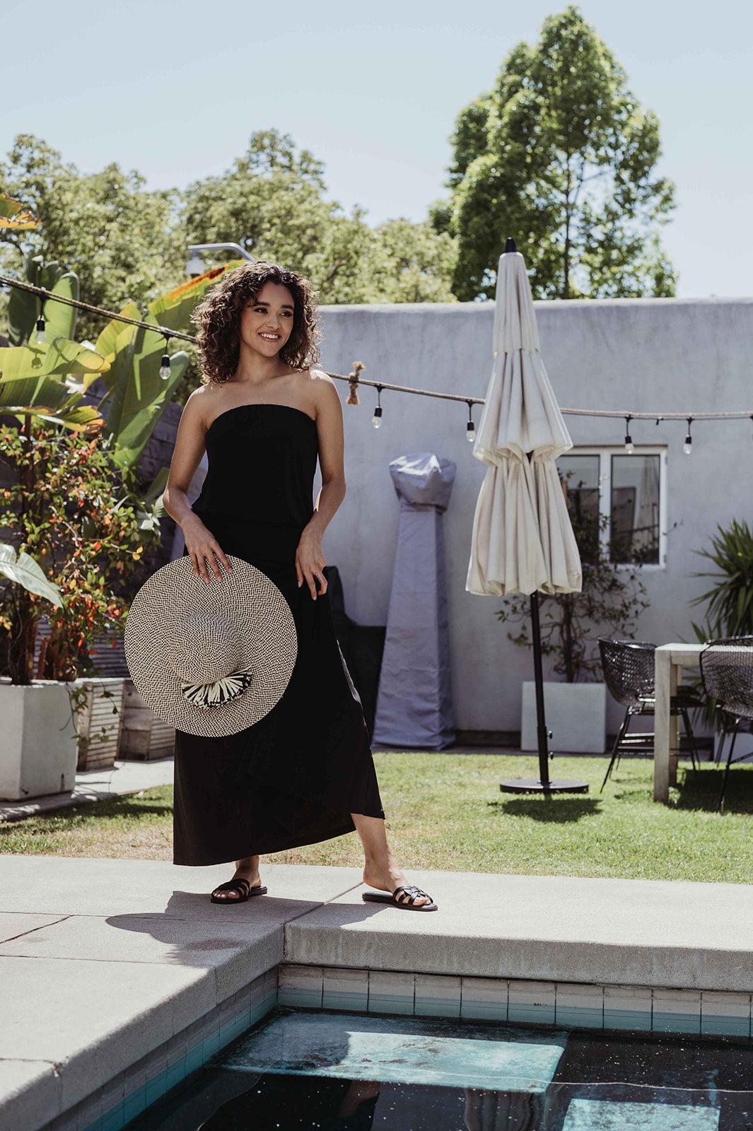 black strapless maxi dress on woman holding large hat