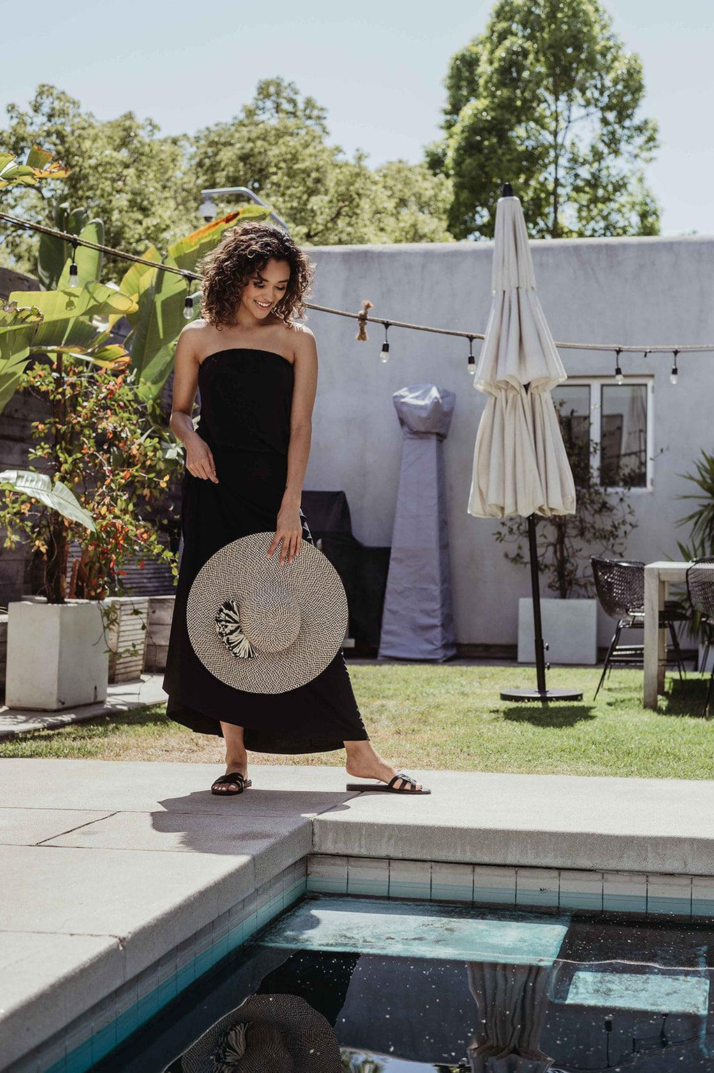 black strapless maxi dress on woman holding large hat