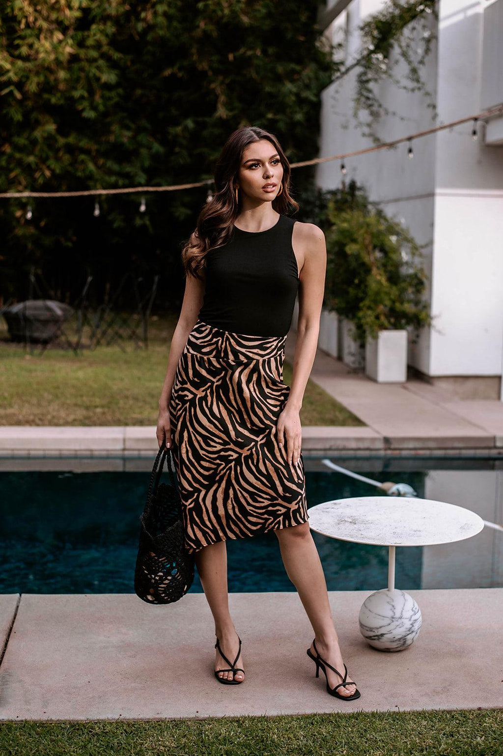 black sleeveless cropped top and animal print skirt on woman