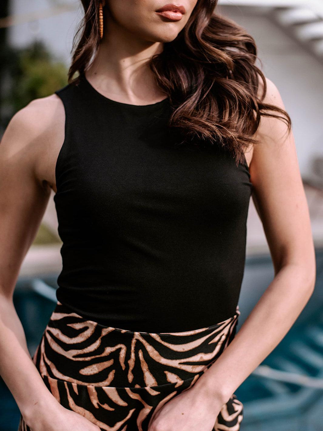 black sleeveless cropped top and animal print skirt on woman