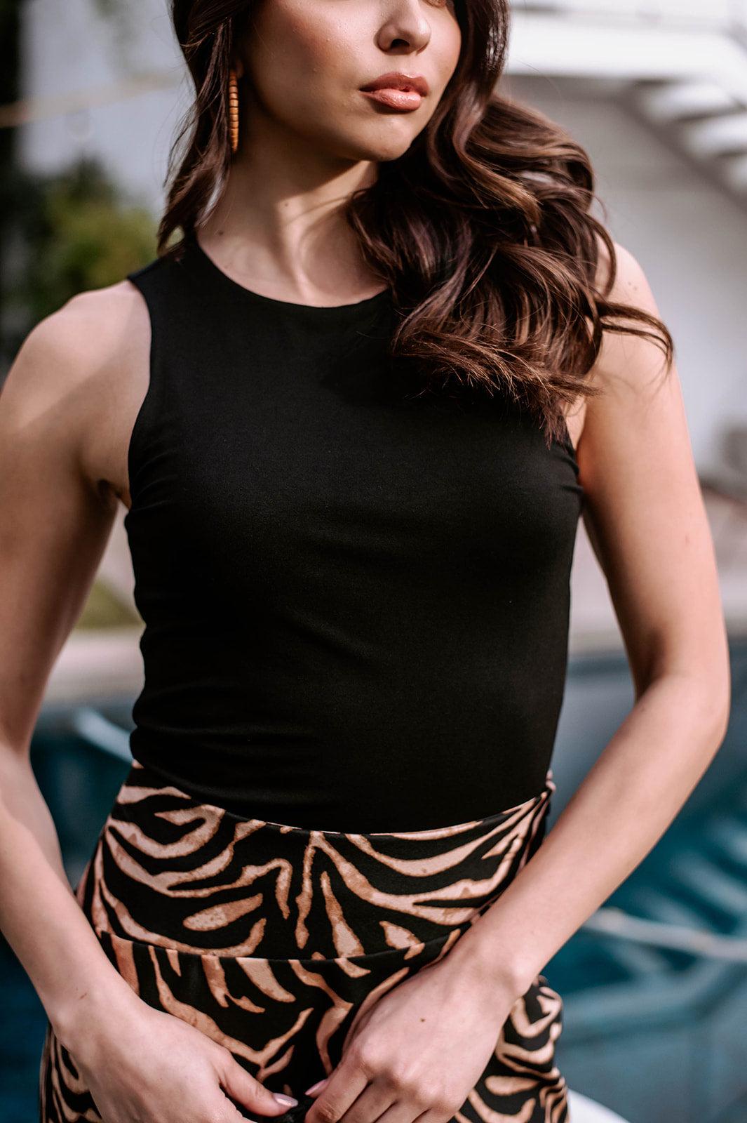 black sleeveless cropped top and animal print skirt on woman