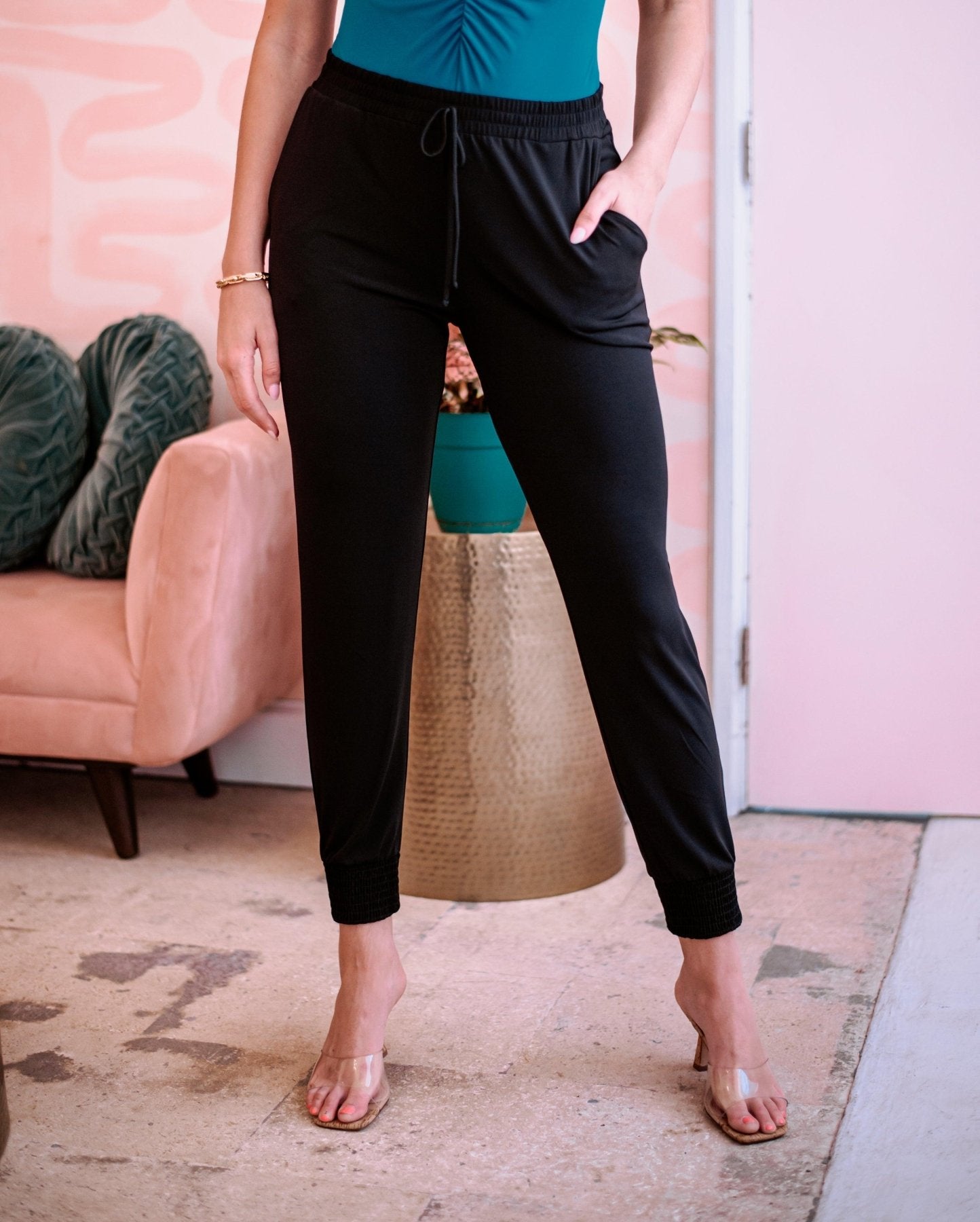 black tapered jogger pants on woman in blue sleeveless top and high heels