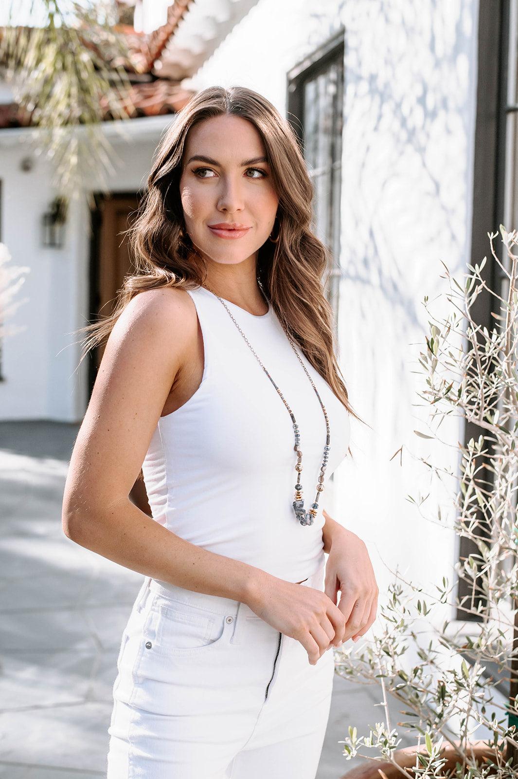 white sleeveless top on woman in white denim pants