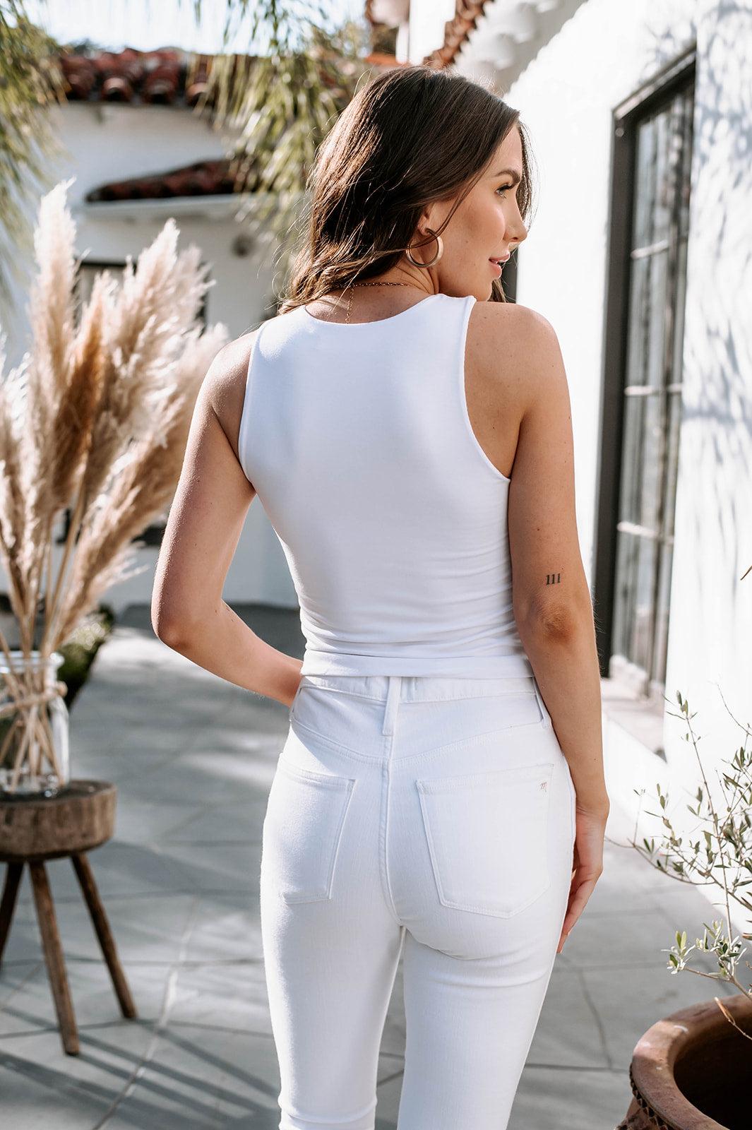 back side of white sleeveless top on woman in white denim pants