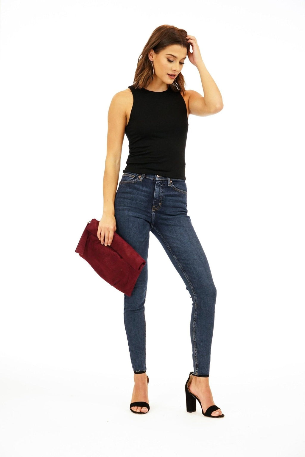 black sleeveless cropped top and dark denim pants on woman in black heels