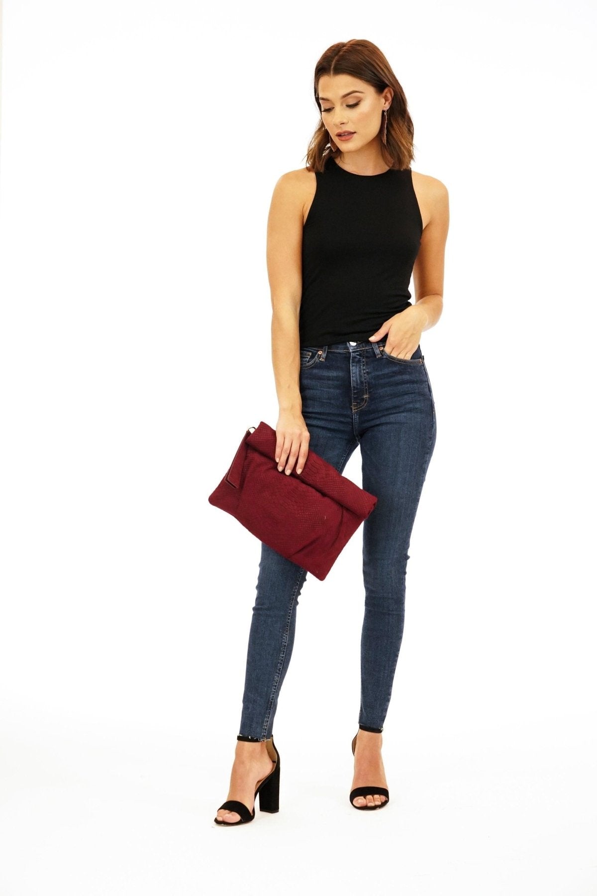 black sleeveless cropped top and dark denim pants on woman in black heels