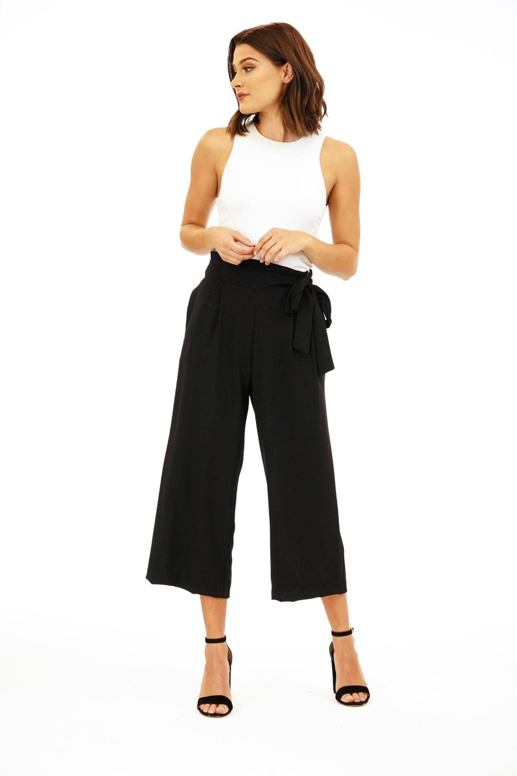 white sleeveless top on woman in black pants and black high heels