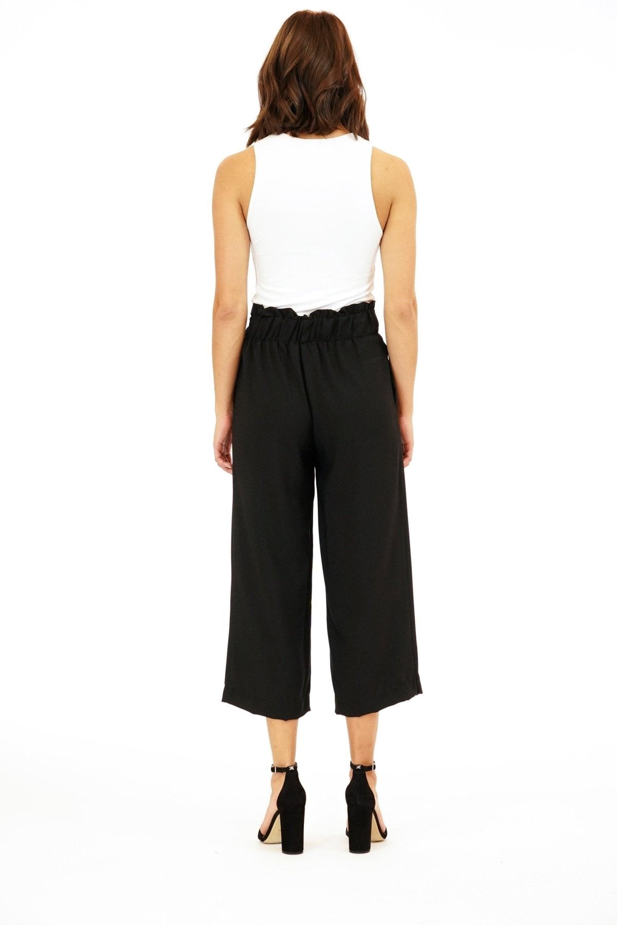 back side of white sleeveless top on woman in black pants and black high heels