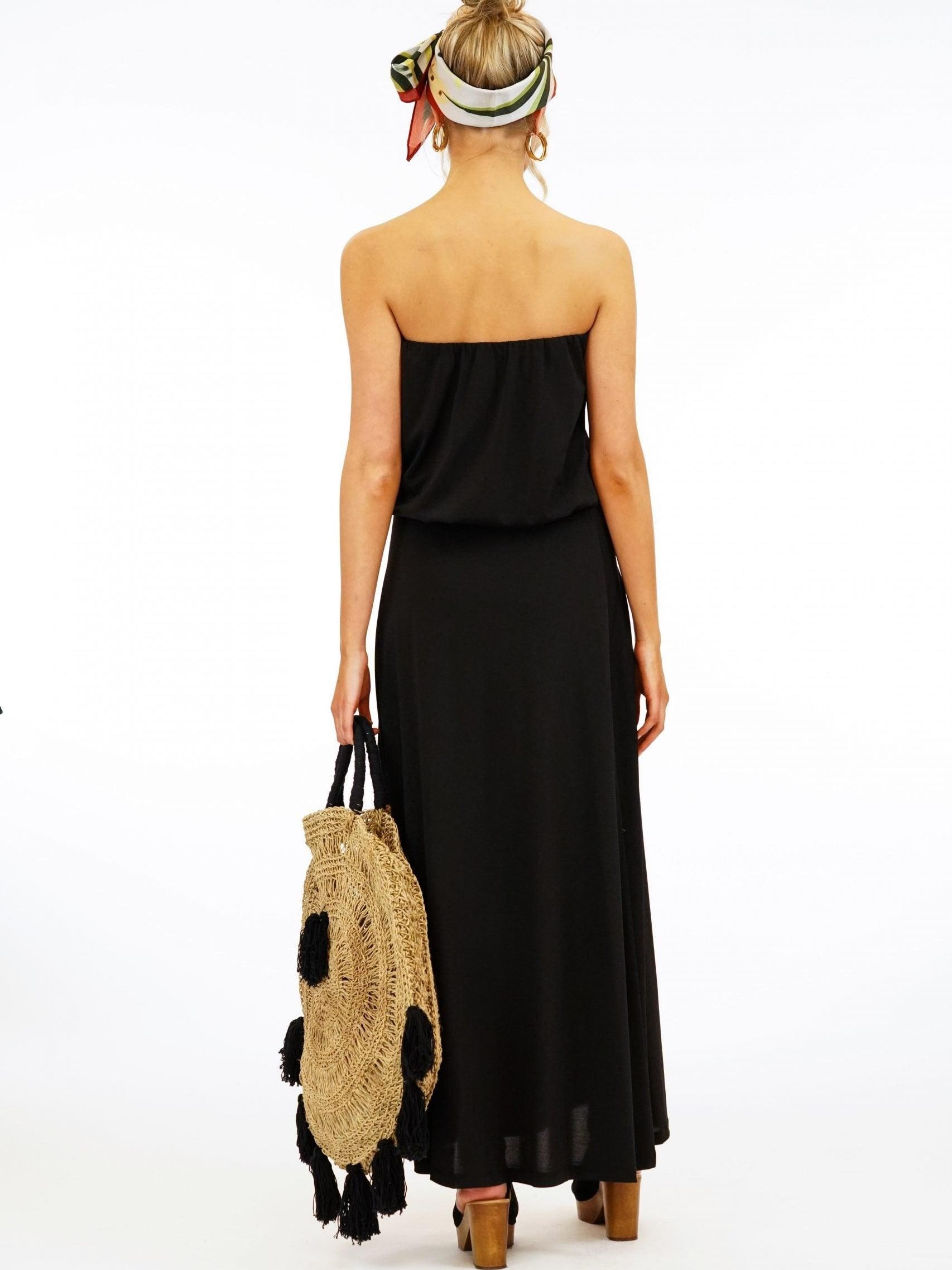 back side of black strapless maxi dress on woman holding large purse