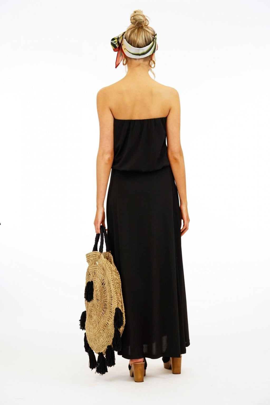 back side of black strapless maxi dress on woman holding large purse