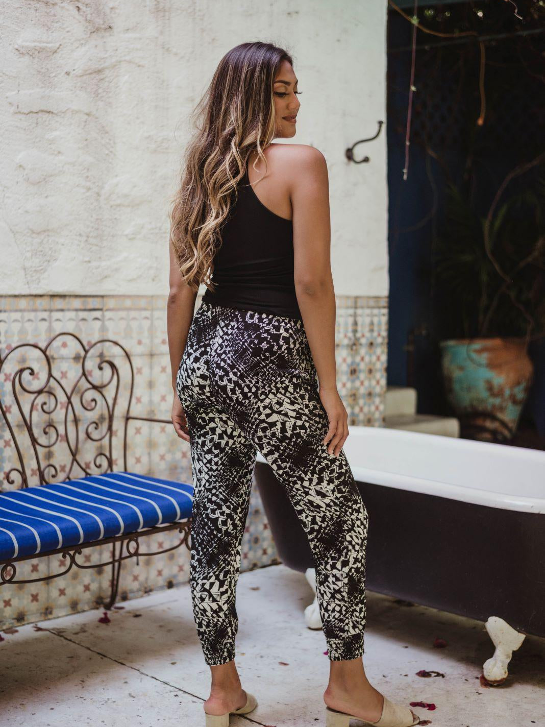 back side of black sleeveless tank top and printed tapered pants on woman