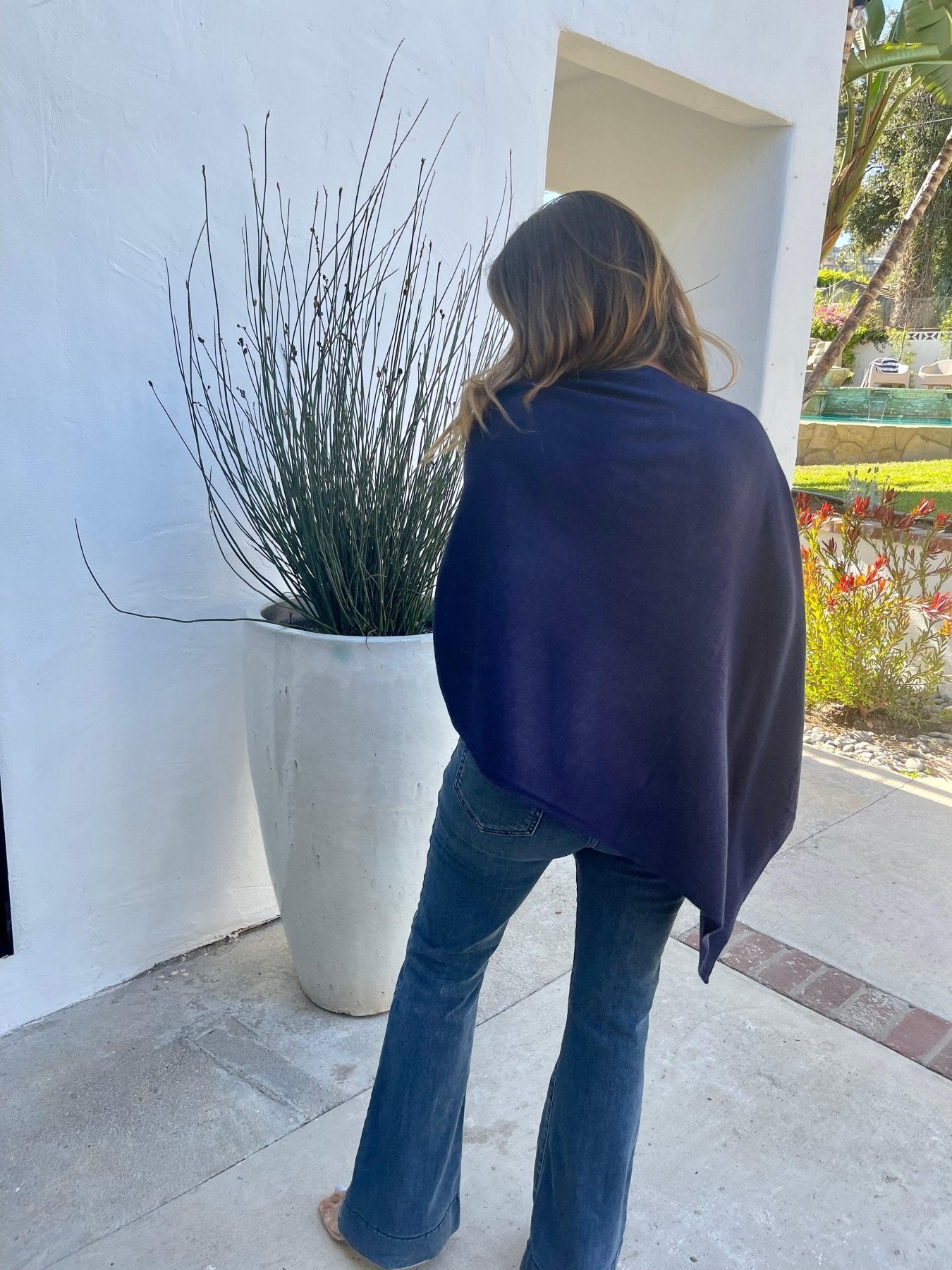 back side of navy poncho and dark denim on woman