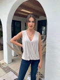 beige sleeveless blouse on woman in dark denim pants